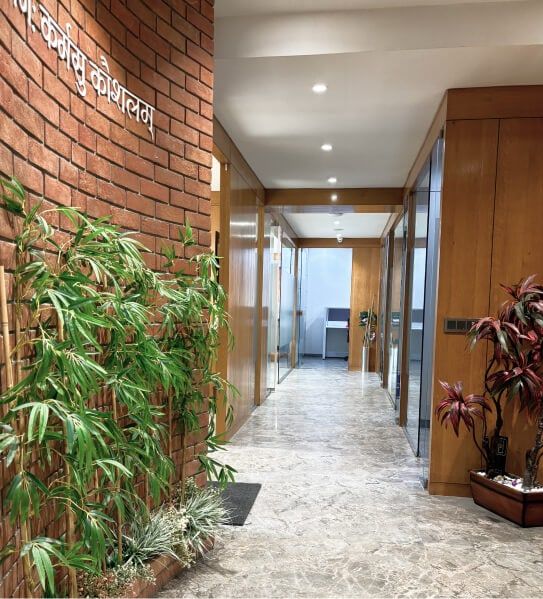 A corridor in the Aakash office lined with brick, timber panels and plants.